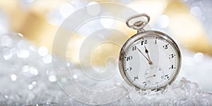 New Years eve countdown. Minutes to midnight on an old pocket watch, bokeh background