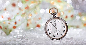 New Years eve countdown. Minutes to midnight on an old pocket watch, bokeh background