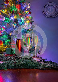 New years eve decoration with christmas tree and clock on the wall as a background and champagne in foreground.