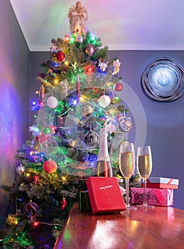 New years eve decoration with christmas tree and clock on the wall as a background and champagne in foreground.