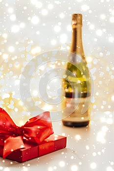 New Years Eve holiday champagne bottle and a gift box and shiny snow on marble background