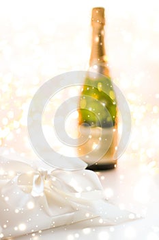 New Years Eve holiday champagne bottle and a gift box and shiny snow on marble background