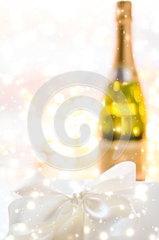New Years Eve holiday champagne bottle and a gift box and shiny snow on marble background