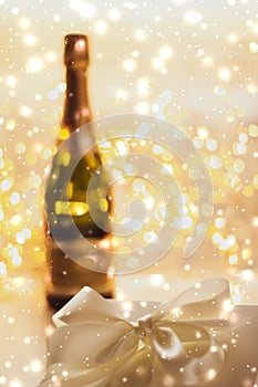 New Years Eve holiday champagne bottle and a gift box and shiny snow on marble background