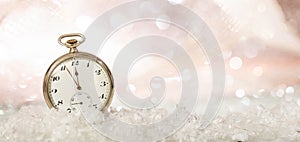New Years eve party celebration. Minutes to midnight on an old fashioned pocket watch, bokeh snowy background, copy space