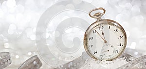 New Years eve party celebration. Minutes to midnight on an old fashioned watch, bokeh festive background