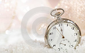 New Years eve party celebration. Minutes to midnight on an old watch, bokeh snowy