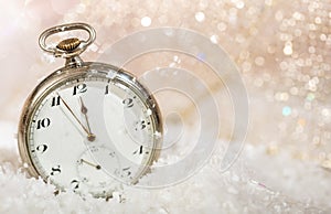 New Years eve party celebration. Minutes to midnight on an old watch, bokeh snowy background