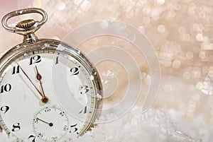 New Years eve party celebration. Minutes to midnight on an old watch, bokeh snowy background