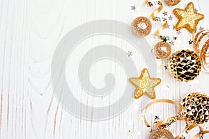 New Years Eve side border of confetti, streamers and gold decorations, overhead view on a white wood background