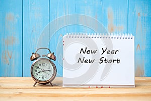 New years New Start text on notebook and retro alarm clock on table and copy space.