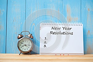 New years Resolutions text on notebook and retro alarm clock on table and copy space. Goals, Mission and New Start