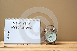 New years Resolutions text on notebook and retro alarm clock on table and copy space. Goals, Mission and New Start