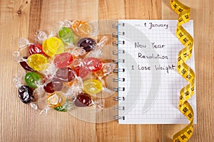 New years resolutions written in notebook, candies and tape measure