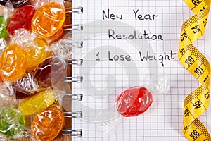 New years resolutions written in notebook, candies and tape measure