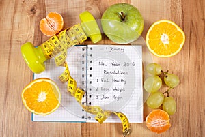 New years resolutions written in notebook and dumbbells with centimeter