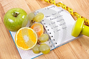 New years resolutions written in notebook and fruits, dumbbells with centimeter