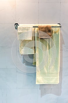 New yellow and brown folded towels hanging on metal rail under l
