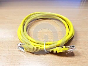New yellow LAN Local Network Area cable on the wooden table - Technology and wire cabling