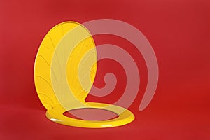 New yellow plastic toilet seat on red background, space for text