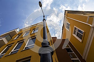 A new yellow residential building photographed from low on the background of a beautiful blue sky with white clouds.