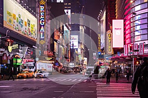 New York, Broadway streets at night. Illuminated high buildings, colorful neon lights, ads and people walking