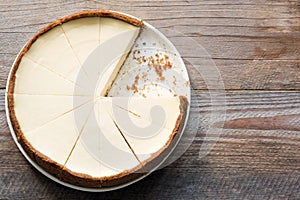 New York Cheesecake or Classic Cheesecake sliced on rustic wood, top view