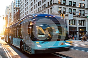 New York City bus driving down 23rd Street through Manhattan with sunlight background