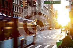 New York City bus driving through the intersection of 23rd Street and 5th Avenue in Manhattan with the light of sunset shining