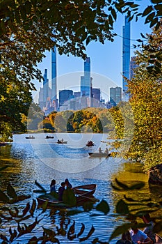 New York City Central Park pond with boats and large city buildings in background