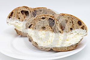 New York City Cinnamon Raisin Bagel Halves filled with Cream Cheese on a White Plate