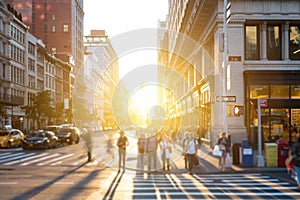 New York City - Bright light of sunset shines on crowds of people crossing the intersection on 5th Avenue in Manhattan