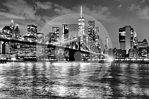 New York City, financial district in lower Manhattan with Brooklin Bridge at night, USA. BW