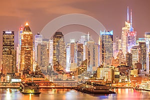 New York City Manhattan downtown at dusk with skyscrapersâ€™ lights illuminated over Hudson River panorama.