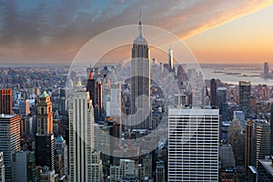 New York City. Manhattan downtown skyline with illuminated Empire State Building and skyscrapers at sunset.