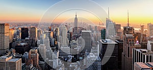 New York City. Manhattan downtown skyline with illuminated Empire State Building and skyscrapers at sunset.