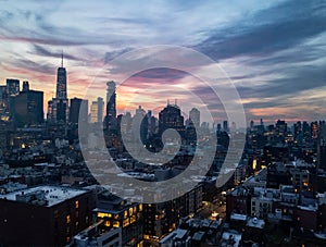 New York City skyline lights at dusk with colorful sky above the buildings of Lower Manhattan