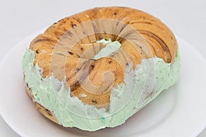 New York City Style Cinnamon Raisin Bagel with Pistachio Cream Cheese on a White Plate