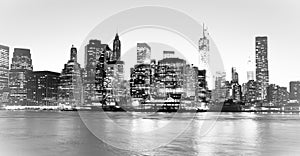 New York Financial District and the Lower Manhattan at night viewed from the Brooklyn Bridge Park. High key black and white image