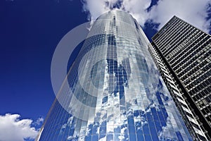 New York, New York: Clouds in a blue sky reflected in the steel and glass facade of a modern skyscraper