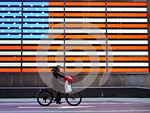 New York, United States, USA March 24, 2020: heoric essential worker with protective mask riding bicycle in front of