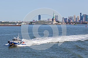 NYPD boat patrolling East River. In the background Statue of Liberty and skyscrapers New Jersey.
