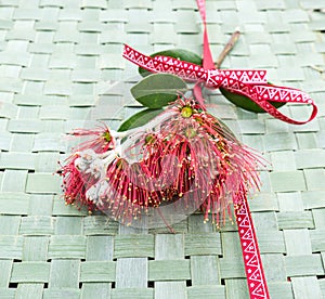 New Zealand Christmas Tree or Pohutukawa flower on woven flax kete background with ribbon - kiwiana xmas theme