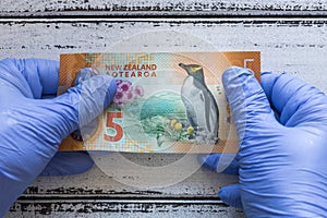 New Zealand five Dollar banknote kept in rubber gloves. The concept of economy and financial threats during the Coronavirus pandem photo