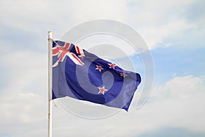 New Zealand flag on blue sky with clouds background