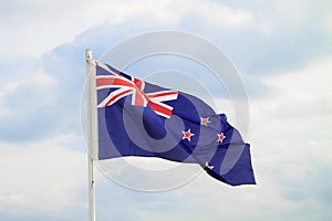 New Zealand flag on blue sky with clouds background