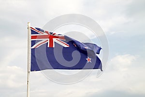 New Zealand flag on blue sky with clouds background