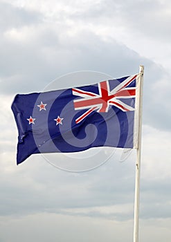 New Zealand flag on blue sky with clouds background