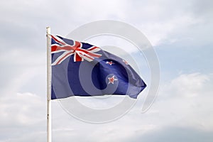 New Zealand flag on a blue sky with clouds background