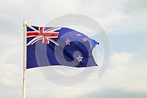 New Zealand flag on a blue sky with clouds background